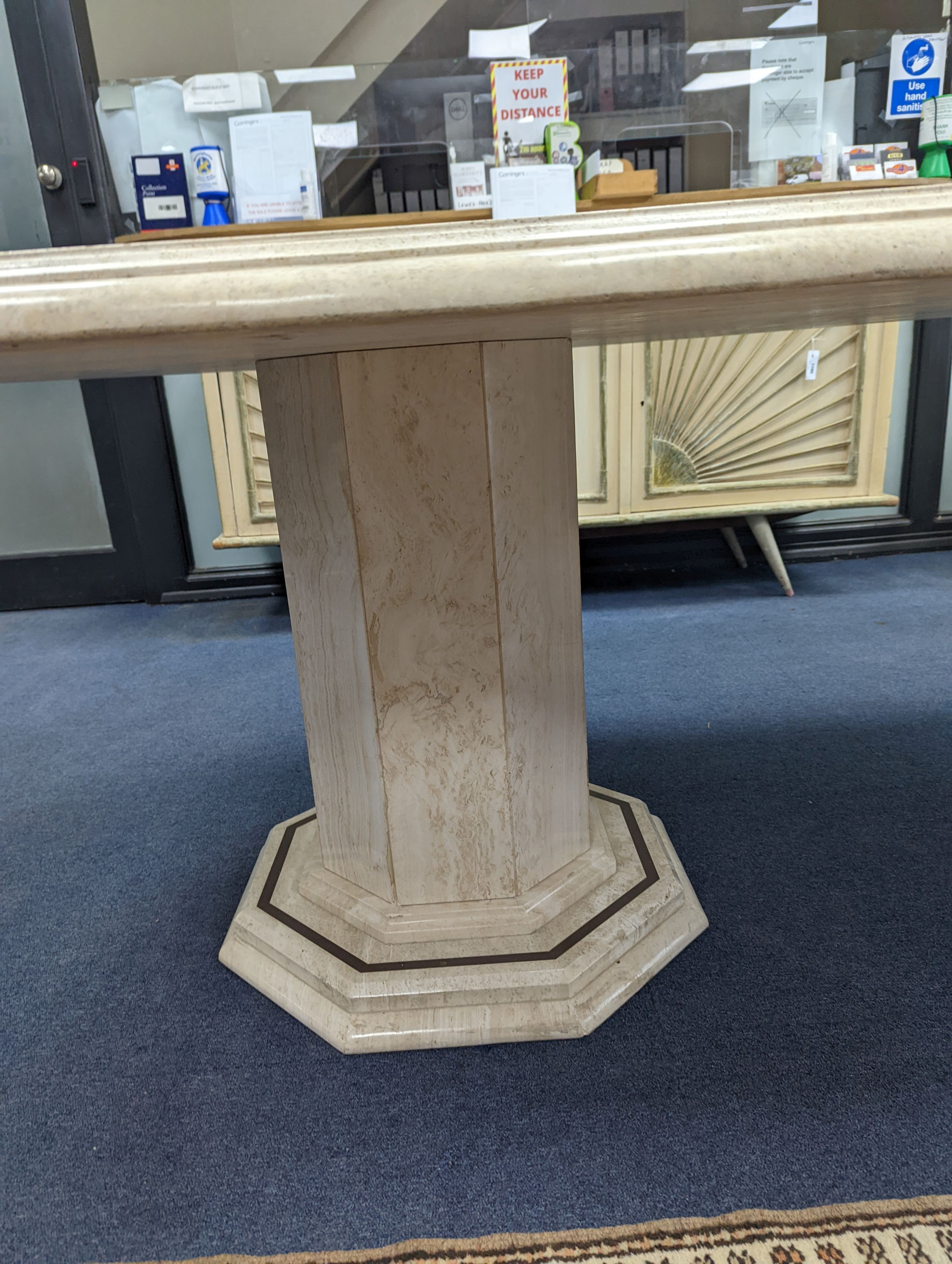 A Travertine marble dining table of elongated ocgtagonal form on twin octagonal column supports, length 260cm, depth 120cm, height 74cm